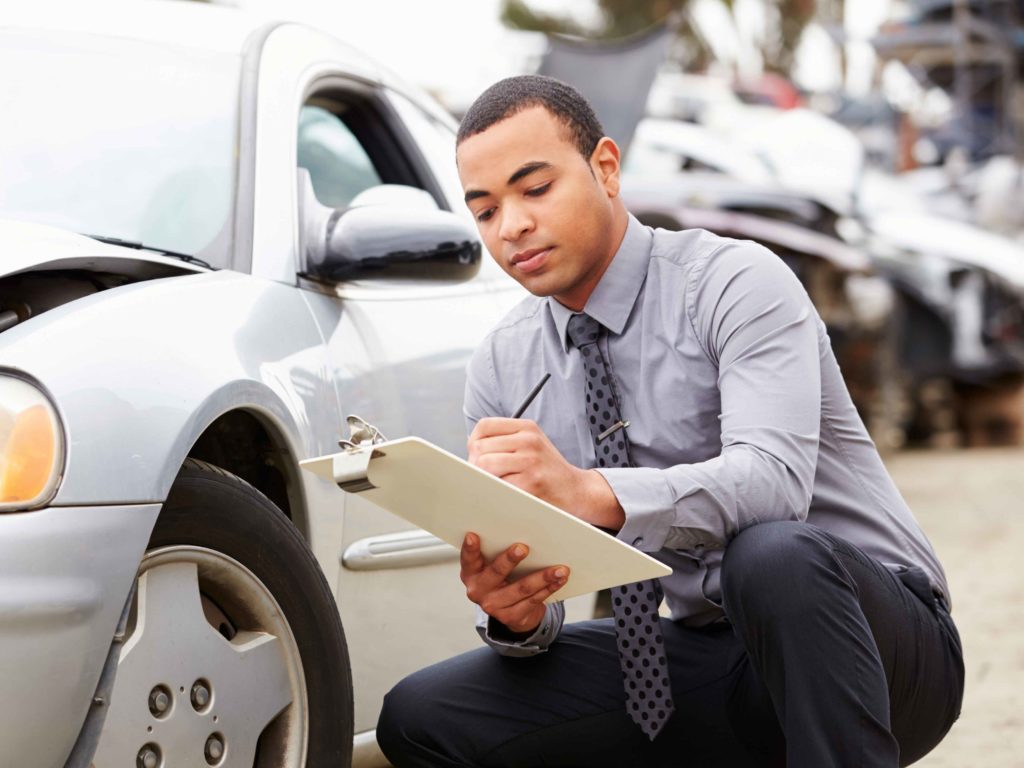 A CurbCheck inspector checking over a used car with a clipboard